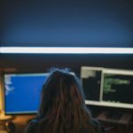 Developer working late at night with dual screens showing code